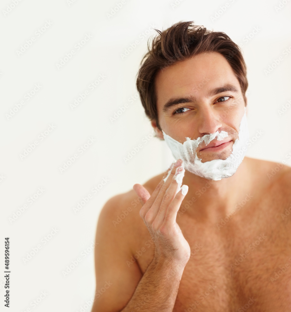 Young guy applying cream to his face for a shave. Portrait of a handsome young man applying cream to his face for a shave.