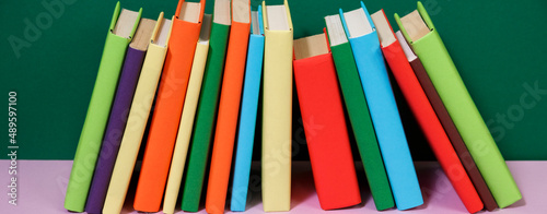 Composition with vintage old hardback books, diary, fanned pages on wooden deck table and colored background. Books stacking. Back to school. Copy Space. Education background.