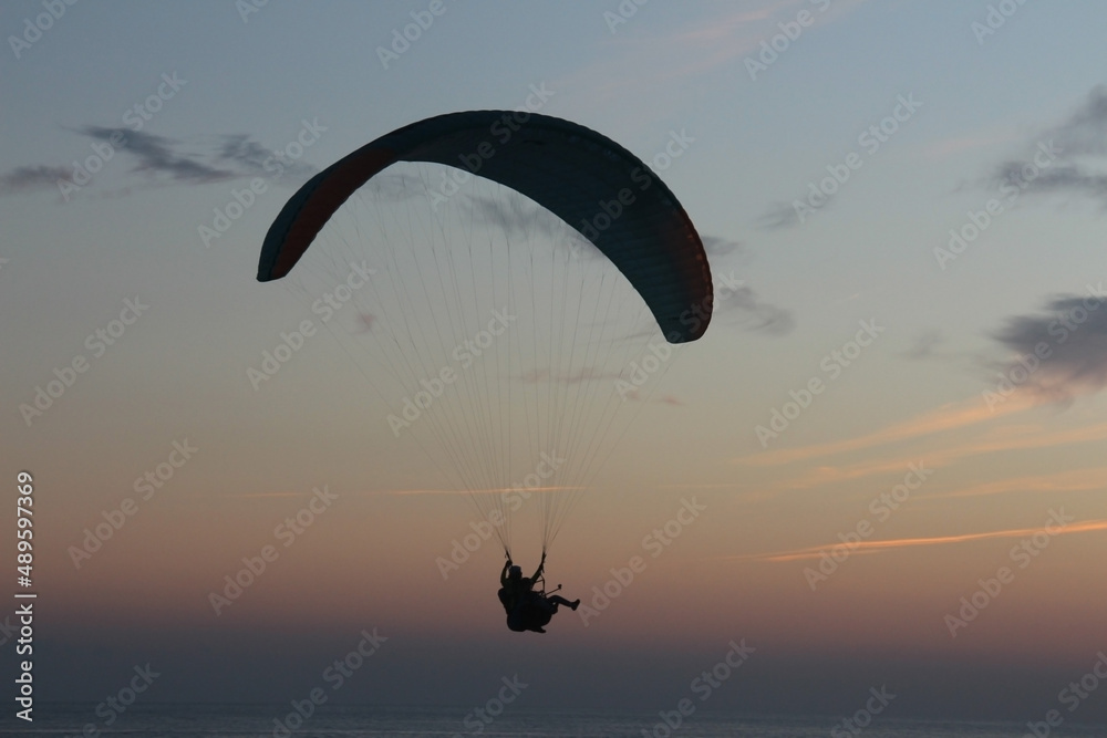 Paragliding silhouette, paraglider pilot fly in sky on beauty nature beach sky background, horizontal photo Paragliding silhouette, paraglider pilot fly in sky on beauty nature beach sky background, horizontal photo