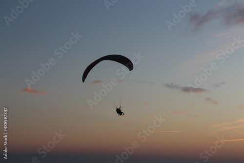 Paragliding silhouette, paraglider pilot fly in sky on beauty nature beach sky background, horizontal photo