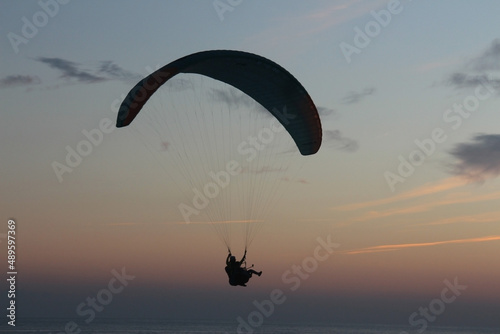 Paragliding silhouette, paraglider pilot fly in sky on beauty nature beach sky background, horizontal photo