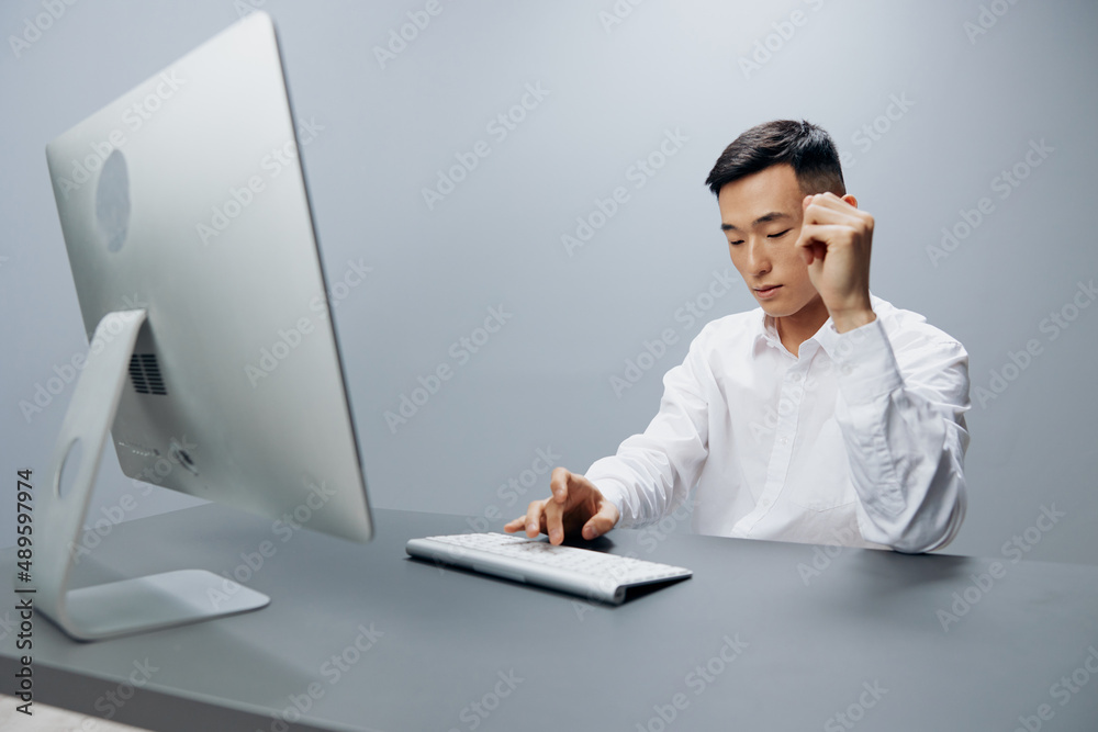 Asian man sit at a desk in front of a computer technologies Asian man sit at a desk in front of a computer technologies
