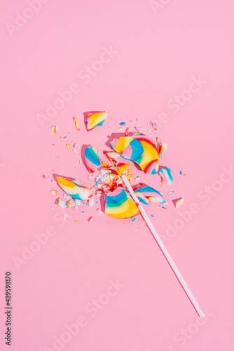 Broken Colorful lollipop on pastel pink background, top view. Candy colours. Minimal Sugar detox, junk food and party concept.