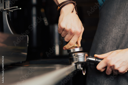 Barista presses ground coffee using tamper. Hand holding the coffee press to brew fresh coffee. 