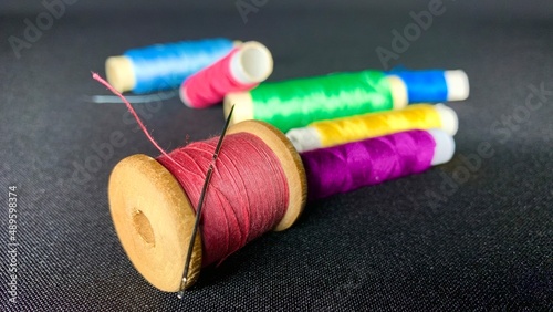 Multi-colored satin threads for sewing wound on spools of different sizes on a black table background