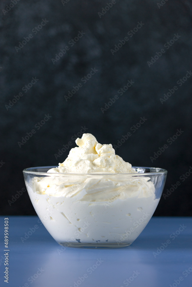 Cooking meringue. Whipped egg in the glass bowl, over gray texture background, blue table. Baking dessert concept. You just need to mix whisked egg whites and sugar. Perfect combination. Copy space. Cooking meringue. Whipped egg in the glass bowl, over gray texture background, blue table. Baking dessert concept. You just need to mix whisked egg whites and sugar. Perfect combination. Copy space.