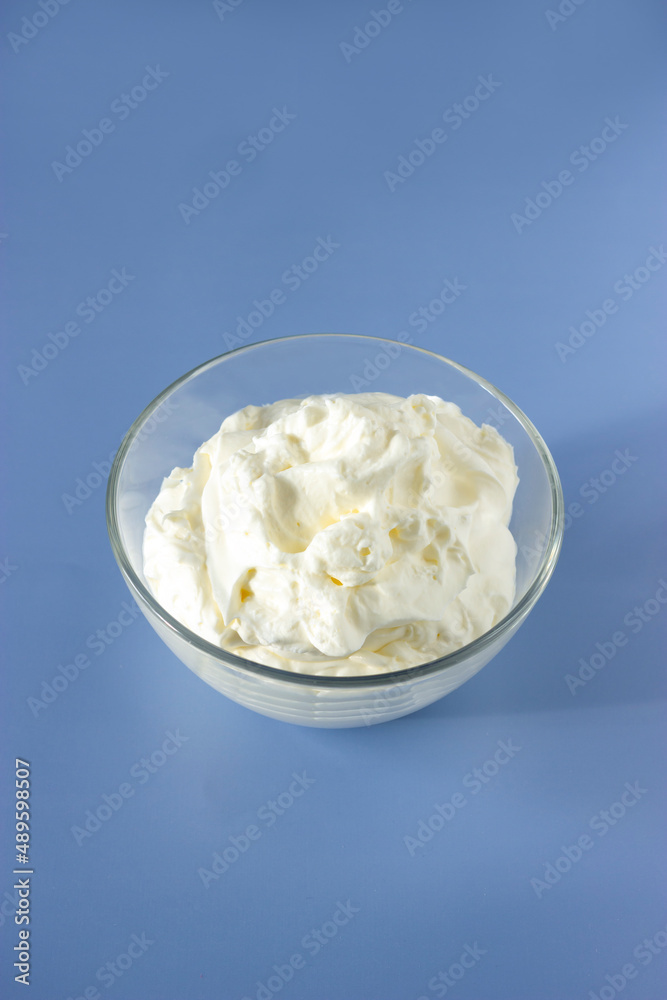 Easy recipe of meringue cookies top view. Vertical plane. Whipped egg whites cream to perfect peaks in glass bowl on blue table. Add some sugar and mix. Cooking at home. Easy recipe of meringue cookies top view. Vertical plane. Whipped egg whites cream to perfect peaks in glass bowl on blue table. Add some sugar and mix. Cooking at home.