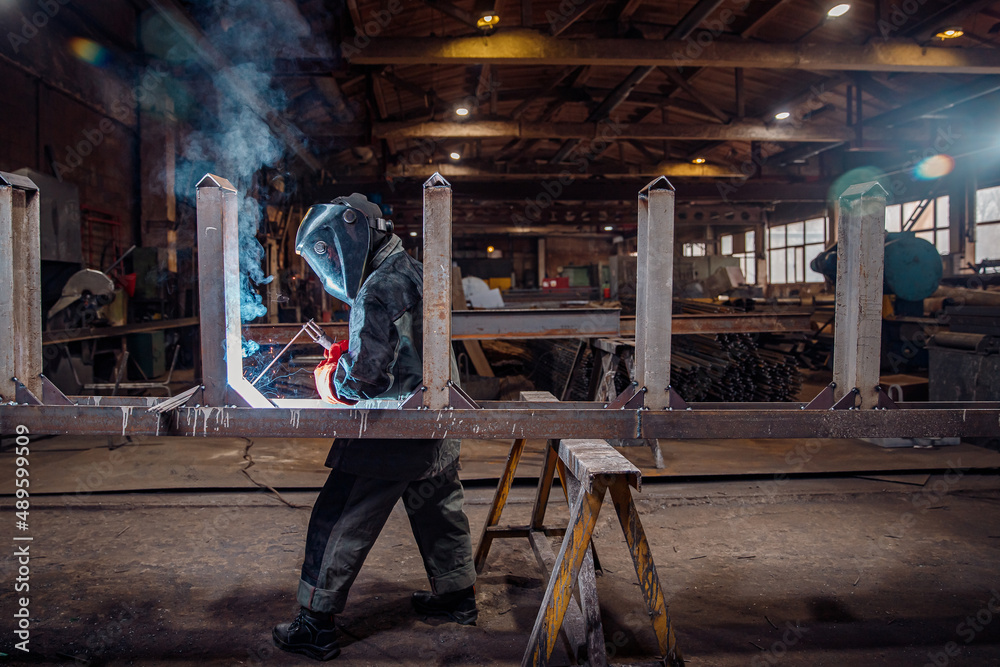 Factory industry worker welder in protective uniform with mask on workplace metalwork