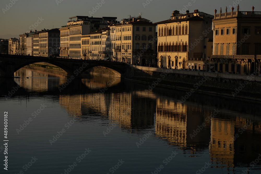 Buildings near the Arno river with water reflections in Florence, Italy