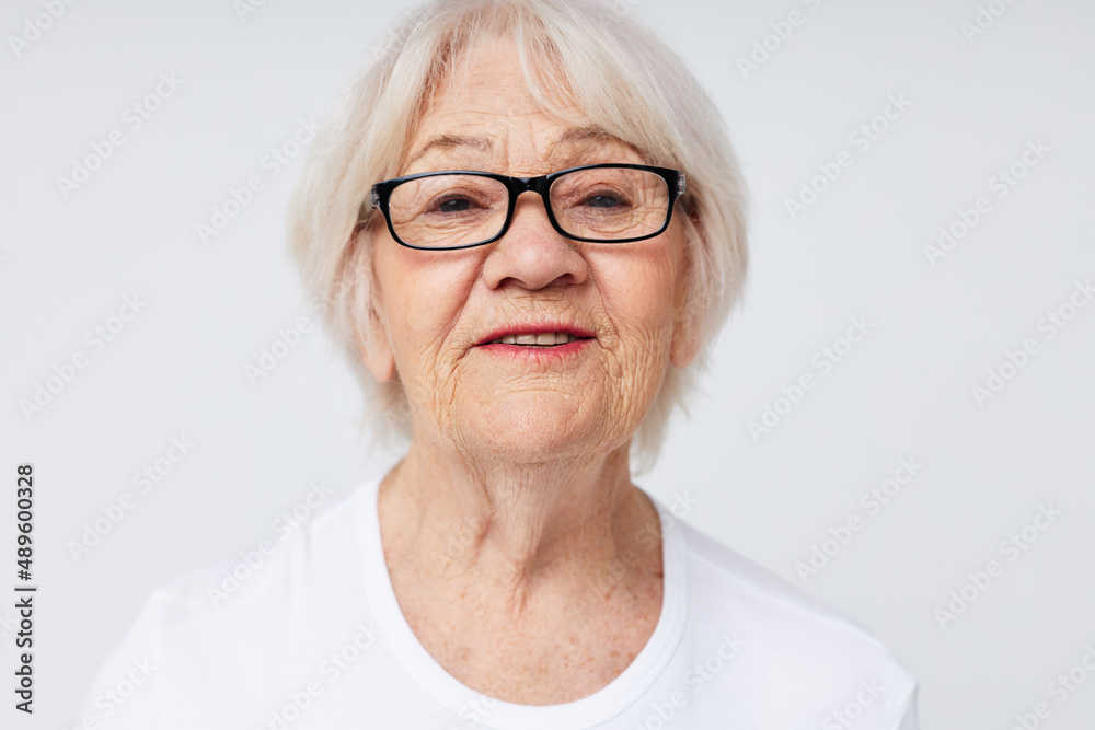 Portrait of an old friendly woman vision problems with glasses light background