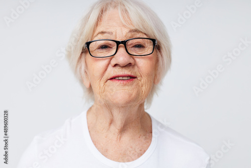 Portrait of an old friendly woman vision problems with glasses light background