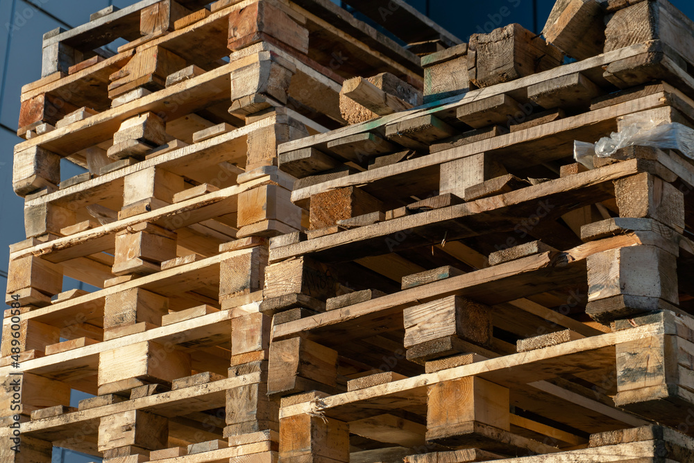 A stack of wooden pallets in an internal warehouse. An outdoor pallet storage area under the roof next to the store. Piles of Euro-type cargo pallets at a waste recycling facility. A stack of wooden pallets in an internal warehouse. An outdoor pallet storage area under the roof next to the store. Piles of Euro-type cargo pallets at a waste recycling facility.