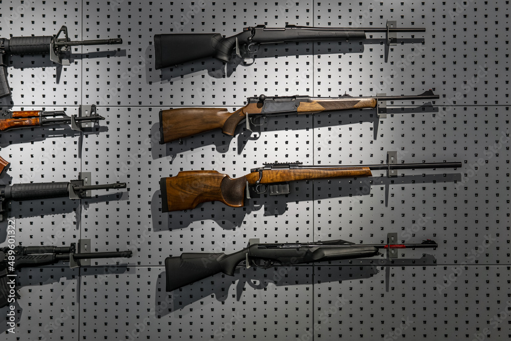 Collection of rifles and carbines. Various firearms hang on special mounts on the wall. Weapon back Collection of rifles and carbines. Various firearms hang on special mounts on the wall. Weapon back