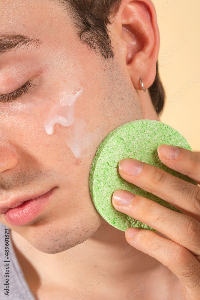 custom made wallpaper toronto digitalYoung and happy man taking care of his skin. Skin care routine. Beautiful model and spa. Isolated beige background.