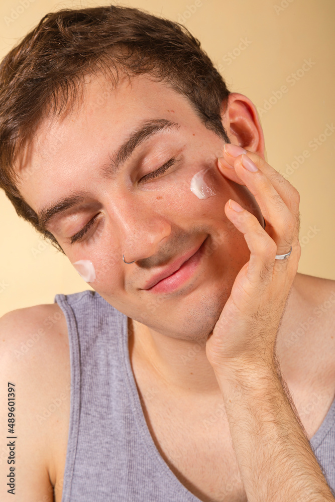 custom made wallpaper toronto digitalYoung and happy man taking care of his skin. Skin care routine. Beautiful model and spa. Isolated beige background.