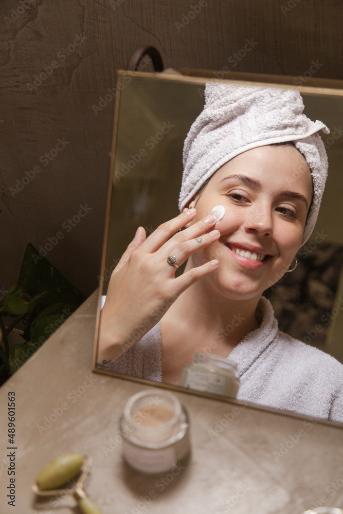 custom made wallpaper toronto digitalportrait young woman uses creams of her face. Isolated on a beige background. Happy healthy model skin care routine
