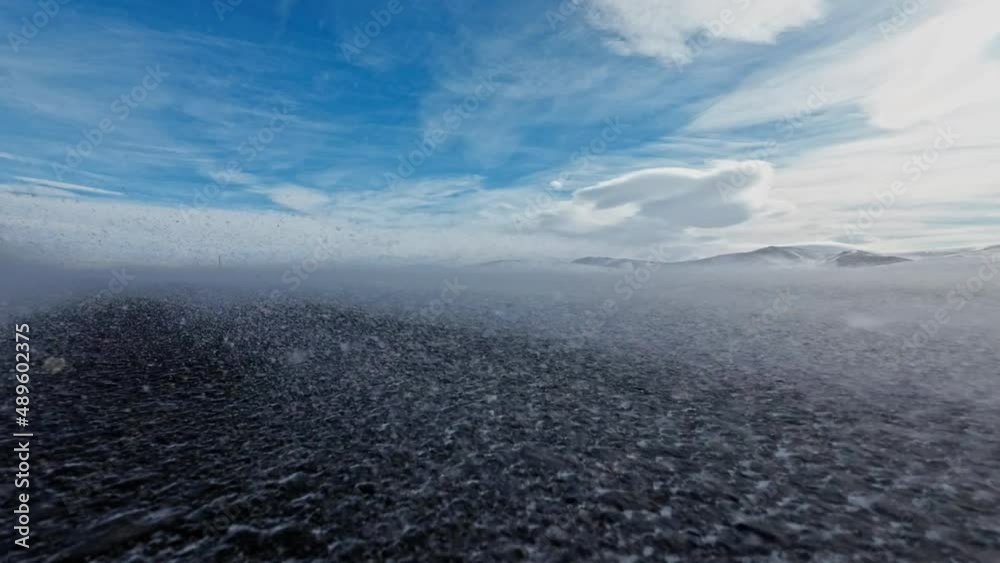 Snowstorm on clear day with blue skies. Asphalt road in snowstorm Snowstorm on clear day with blue skies. Asphalt road in snowstorm