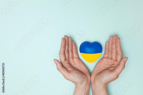 Heart with print the national flag of ukraine in female hands. Flat lay. Copy space.