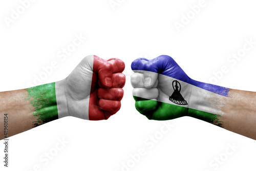 Two hands punch to each others on white background. Country flags painted fists, conflict crisis concept between italy and lesotho