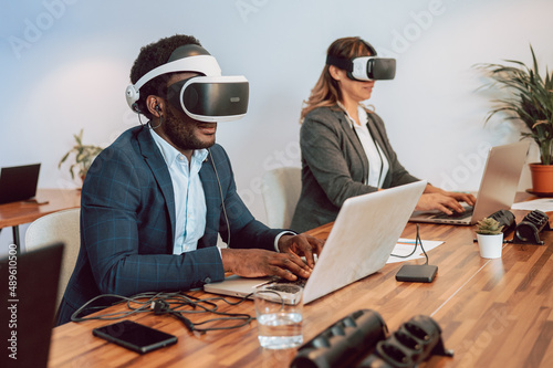 Man with VR headset working on laptop in metaverse photo
