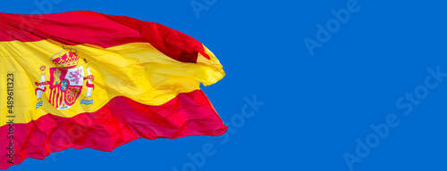 spain flag in the wind with blue sky background. photo