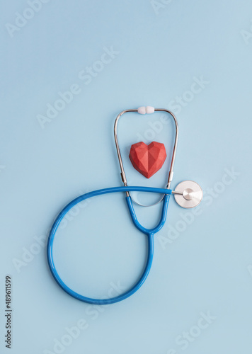 Stethoscope and red polygonal heart on blue background. Vertical banner for medical clinic or center, copy space