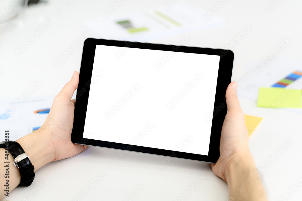 Man holding blank white screen digital tablet with copy space while sitting on working desk