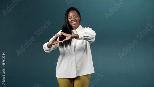 A handsome african woman is showing a heart from her hands 