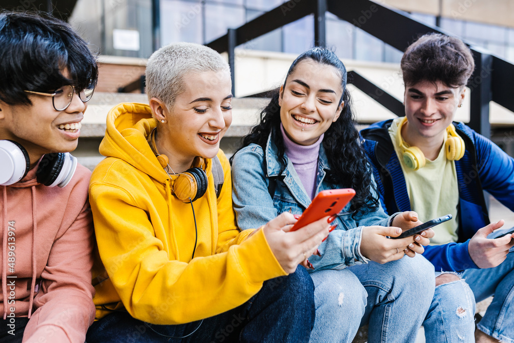 © Xavier Lorenzo - Group of multiracial teenage students using mobile phones on school - Young friends watching social media content on smartphones