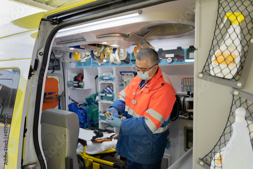 photo of a doctor with gray hair in the ambulance checking the medical material