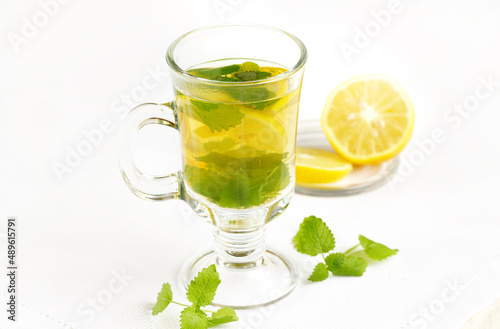 healthy tea with lemon and lemon balm in a transparent glass on a light background, tea for colds and viruses