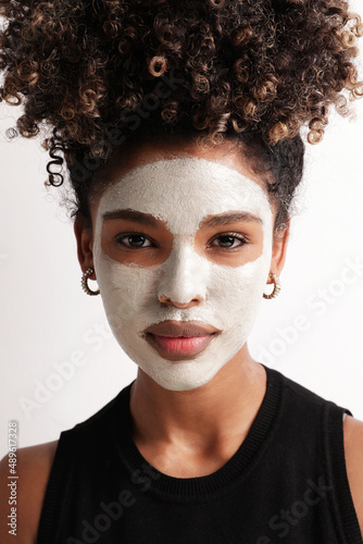 Young woman with moisturising mask on her face looking at the camera. Vertical.