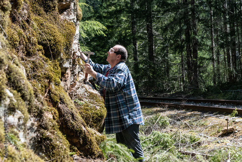 Elder Male Rockhound with Rock Hammer at Rock Face Prospecting for Minerals and Fossils