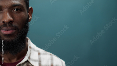 A young black man in a white shirt blinks and looks away