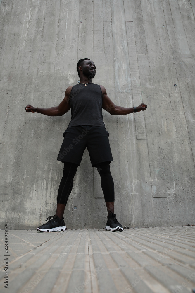 Full-length portrait of Black young man doing hard workout outdoors. Vertical.