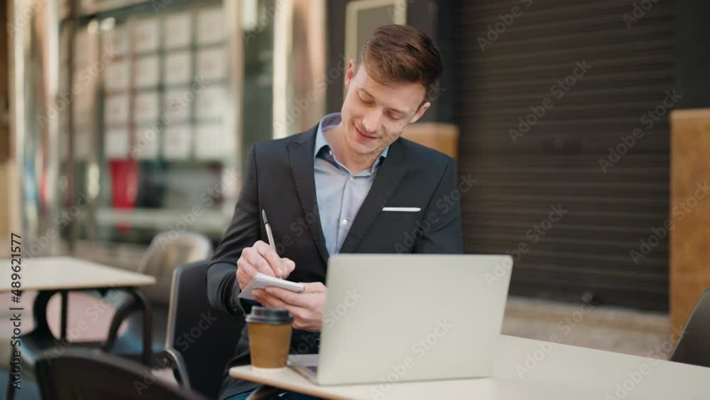 Young caucasian man smiling confident using laptop and writing on notebook at coffee shop terrace Young caucasian man smiling confident using laptop and writing on notebook at coffee shop terrace