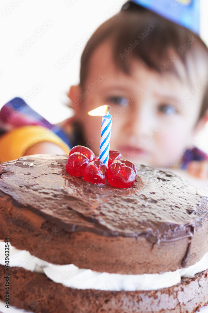 Celebrating a special day. A birthday cake with one candle with the birthday boy in the background. Celebrating a special day. A birthday cake with one candle with the birthday boy in the background.