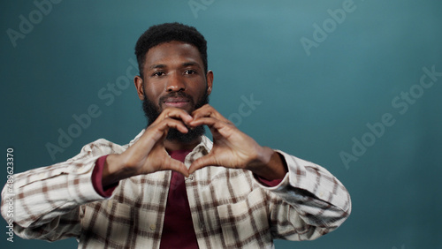 An adult african man is showing a heart from his hands