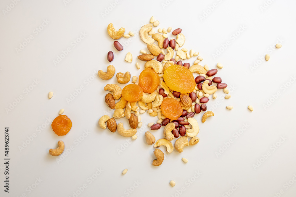 A mixture of dried fruits and nuts. Dried apricot, cashew nuts, almonds, roasted peanuts, pine nuts on a white background. Proper nutrition, healthy lifestyle. A lot of vitamins and nutrients A mixture of dried fruits and nuts. Dried apricot, cashew nuts, almonds, roasted peanuts, pine nuts on a white background. Proper nutrition, healthy lifestyle. A lot of vitamins and nutrients