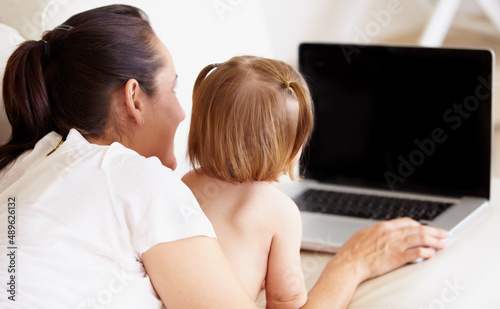 Getting an early start at learning. A mother and her little daughter looking at a laptop together.