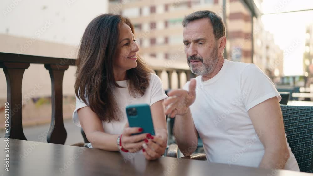 Man and woman couple using smartphone sitting on table at coffee shop terrace Man and woman couple using smartphone sitting on table at coffee shop terrace