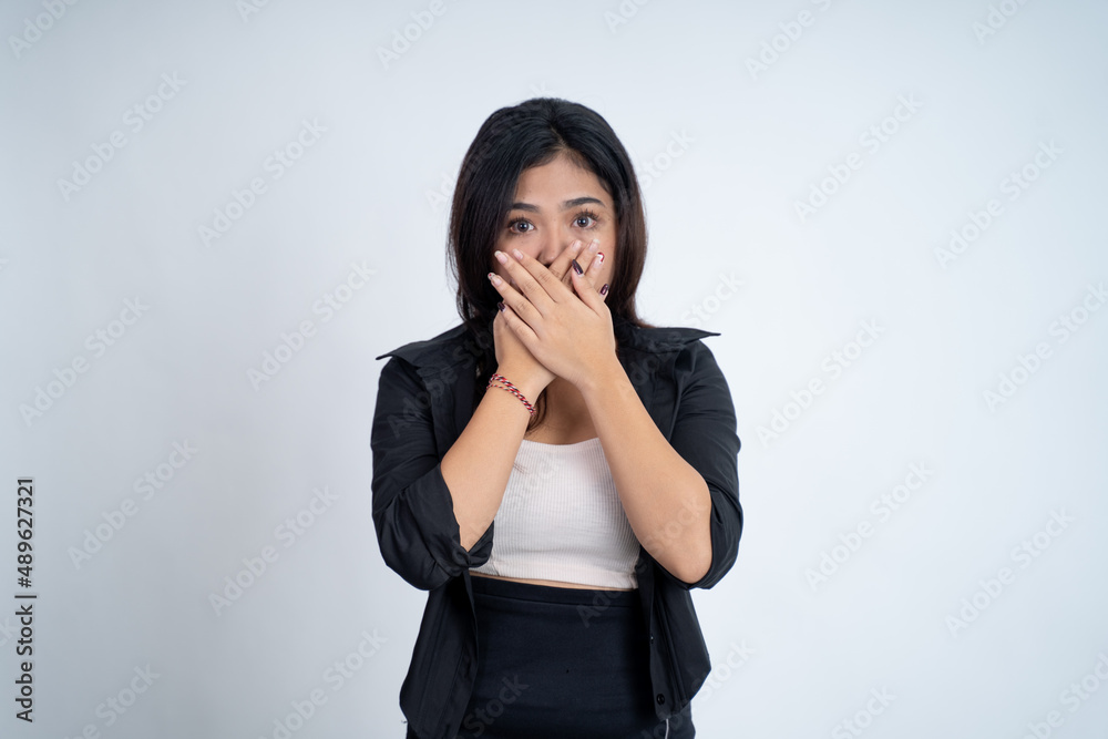 Young woman with shocked expression with hands covering mouth Young woman with shocked expression with hands covering mouth