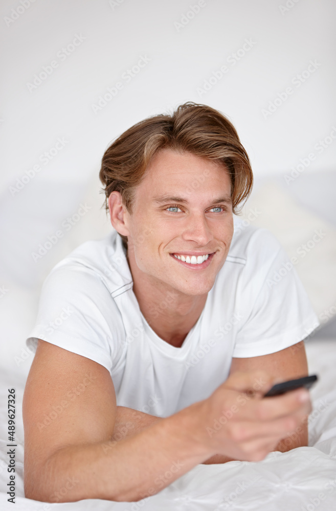 Thats my favorite show. A handsome young man wearing his pjamas and watching tv while sitting in bed. Thats my favorite show. A handsome young man wearing his pjamas and watching tv while sitting in bed.