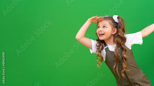 A beautiful little girl looks into the distance. the child looks out from around the corner and looks thoughtfully to the sides.