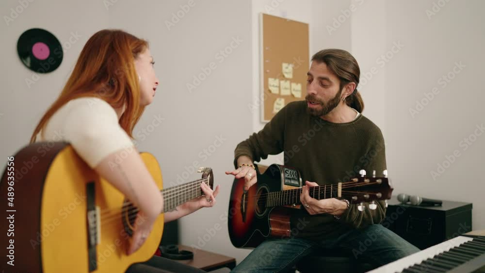 Man and woman having guitar lesson at music studio
