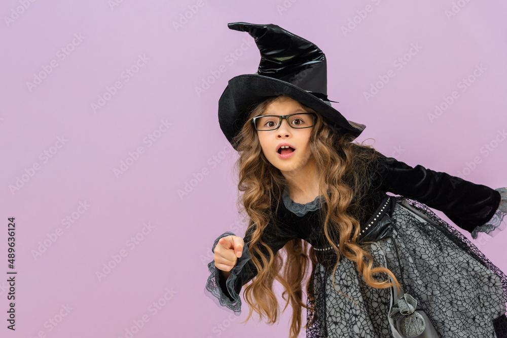 A beautiful little witch is peeking around the corner. An attractive witch on a purple background. A beautiful little witch is peeking around the corner. An attractive witch on a purple background.