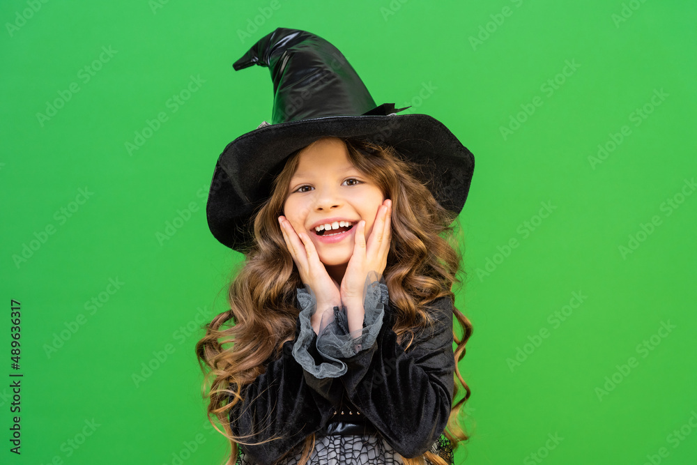 A beautiful little girl in a Halloween witch costume. An attractive child in a sorceress's mantle.