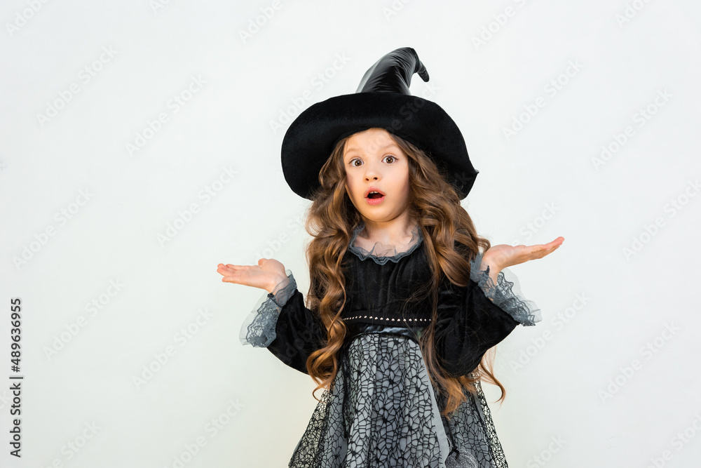 A shocked little witch on an isolated background. a little girl in a Halloween outfit. A shocked little witch on an isolated background. a little girl in a Halloween outfit.