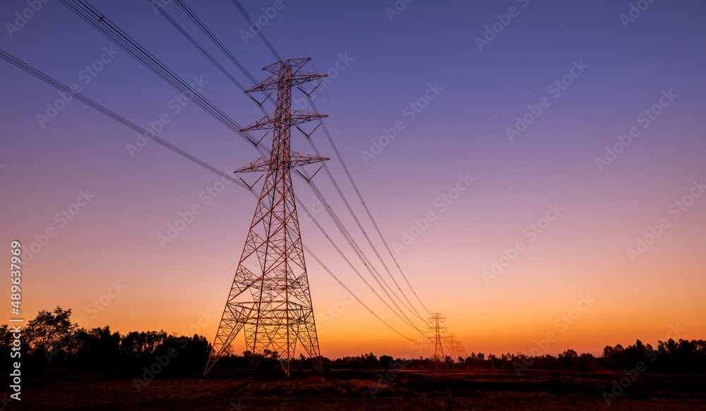 Silhouette street light post, electric pole and high voltage tower.High voltage transmission pole against morning sun background.