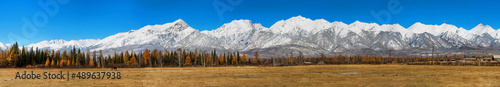 Panorama of nature. Mountainous terrain. Panoramic autumn landscape. A field in the foreground, a village forest and mountains in the distance. Mountain landscape. © Elena Nikko